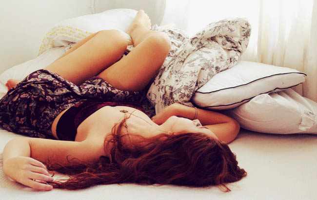 Menina que dorme na cama com capas brancas